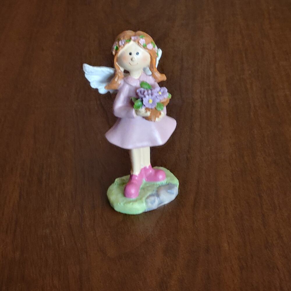 Small decorative figurine of a stylized angel holding a basket of flowers
